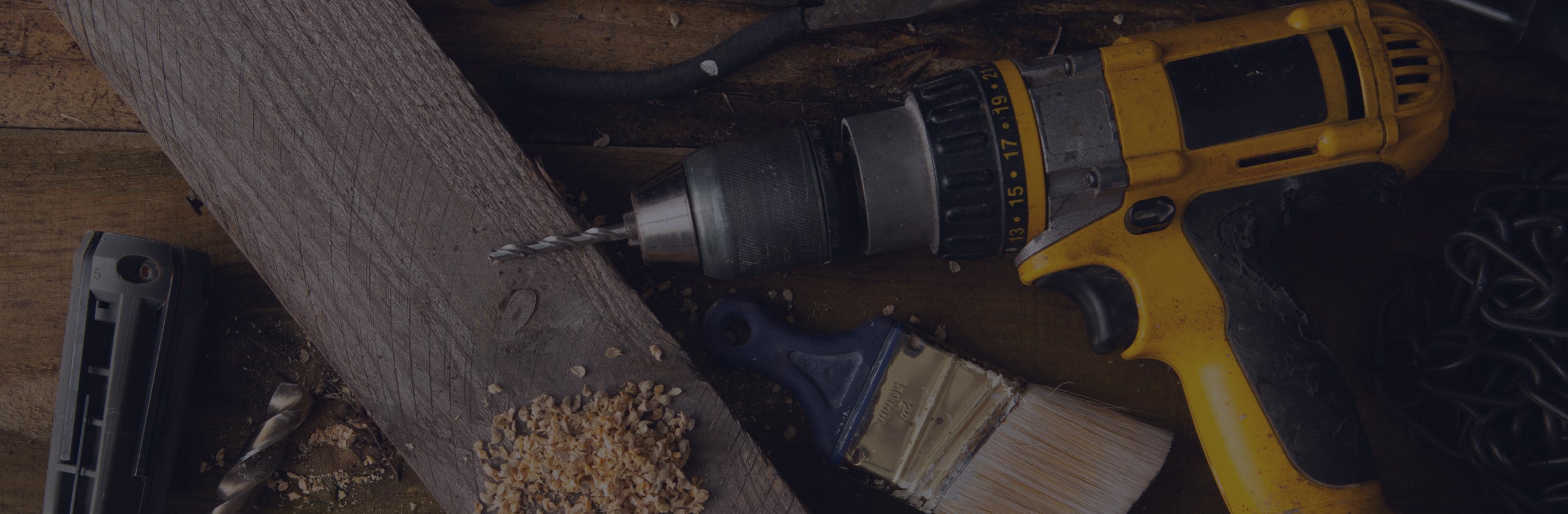 A background image featuring a drill, paint brush, wood and more tools