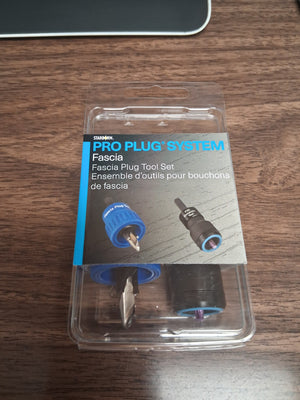 A packaged Trex Starborn Pro-Plug Fascia Tool rests on a wooden desk. Through its clear packaging, two fascia installation tools are visible alongside product details in English and French—making it perfect for efficient fascia board installation.