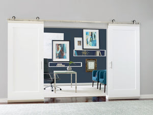 The Jeld-Wen Madison 1-Panel Recessed Slab (12"x80"x1-3/8") barn door opens to a modern office with a desk, chair, blue armchairs, abstract art on dark blue walls, and a plant atop the glass desk in this tidy, inviting space.
