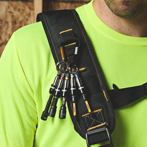 A person in a neon yellow shirt wears a black shoulder strap, which holds a color-coded DEWALT Quick Access Keychain Bit Holder 5 Sleeve and several tools clipped onto carabiner bit holders.