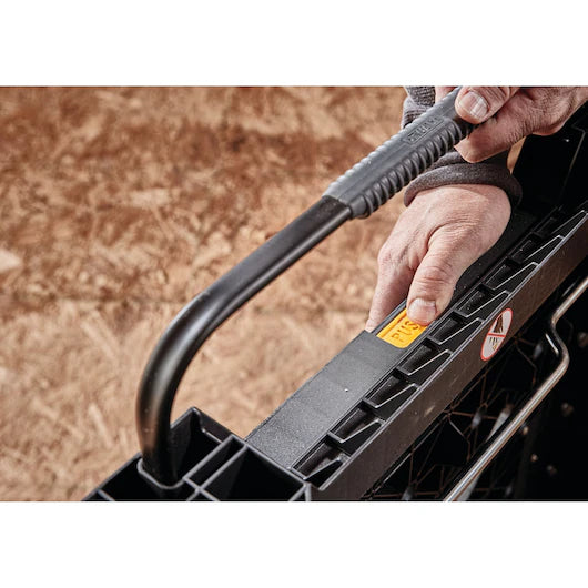A close-up of a person’s hand gripping the handle of a black plastic toolbox, with a PUSH label next to their hand and a caution sticker visible on the side—perfect for use alongside the Dewalt Folding Workbench by TurkstraLumberLtd in any garage or workspace.