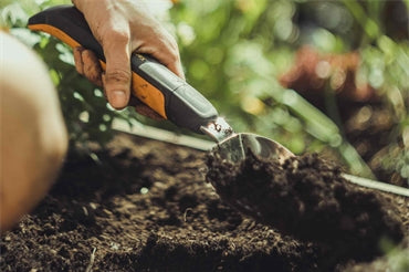 A person gardening with a Fiskars trowel