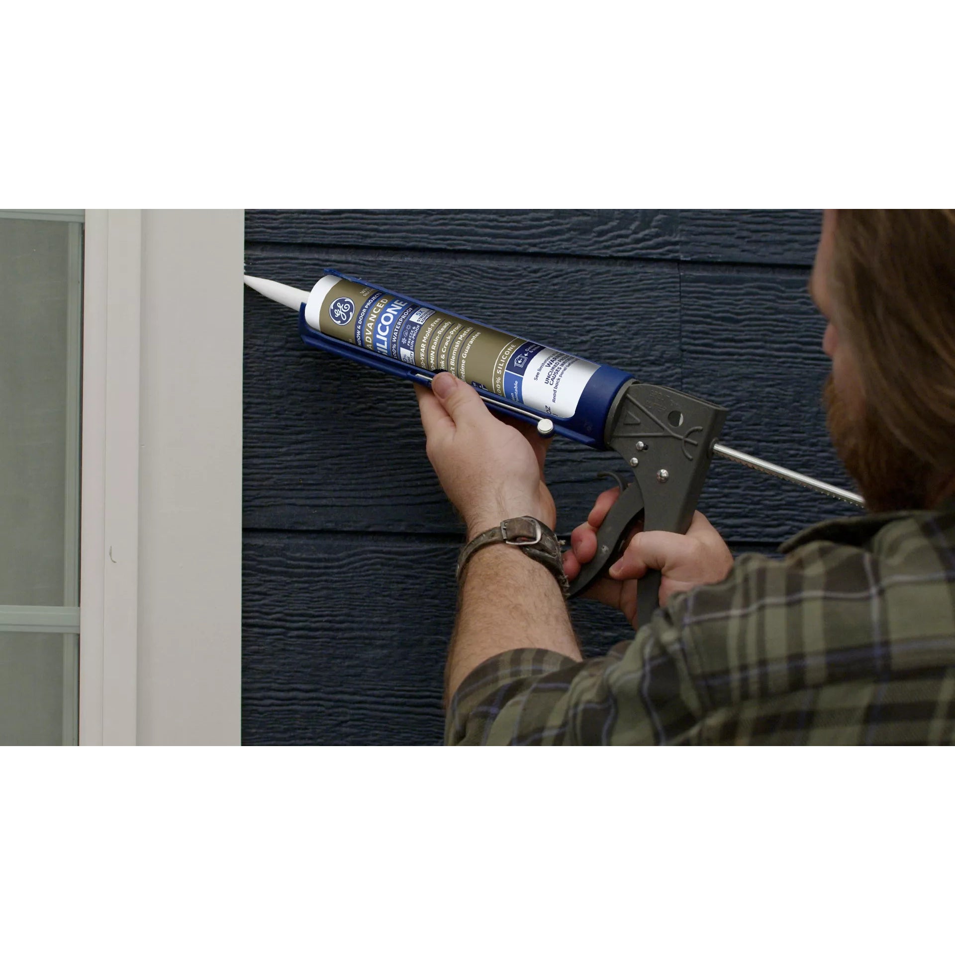 Person applying caulk to a window frame using a caulking gun.