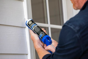 Person applying silicone sealant to a window frame