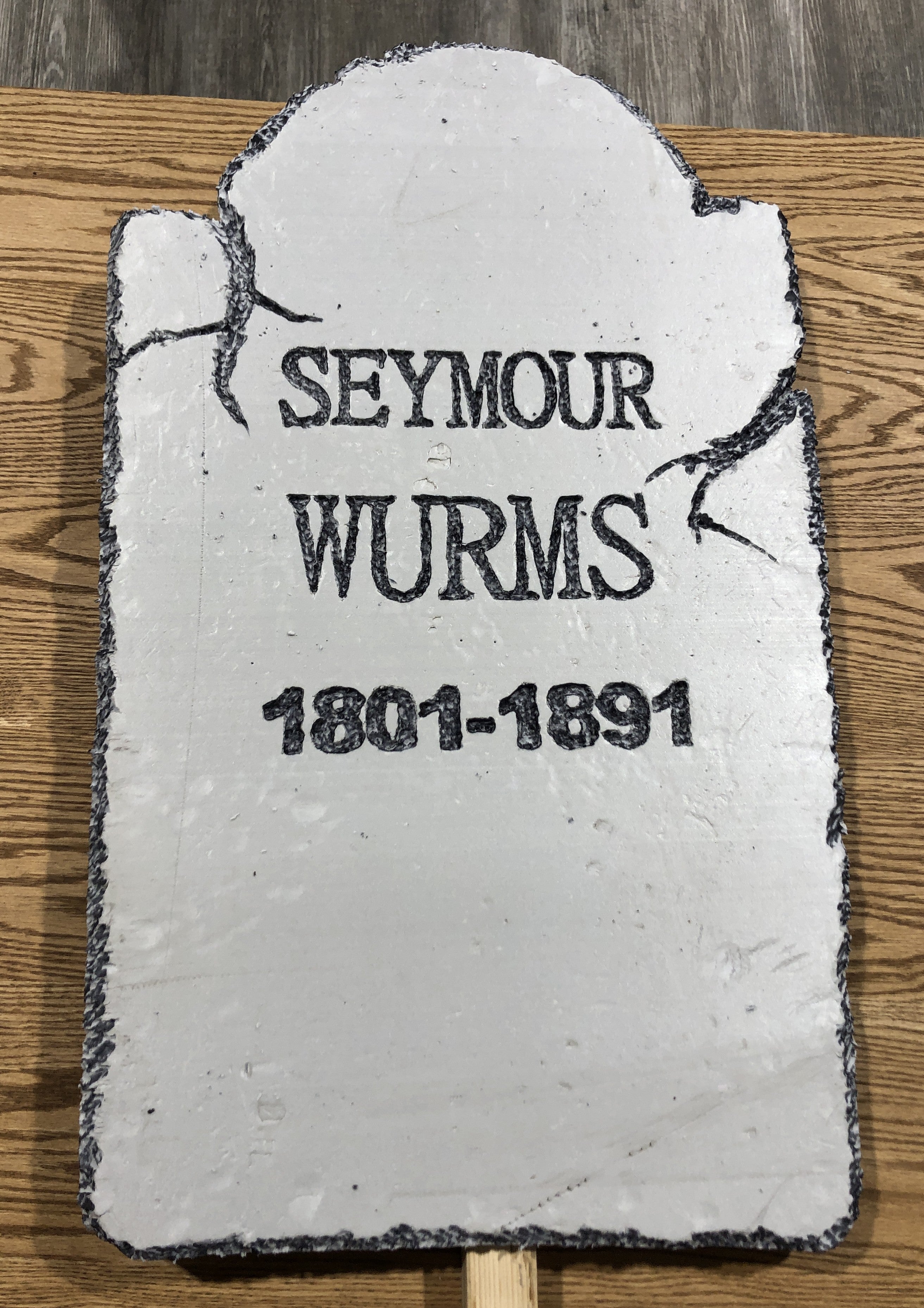 Gravestone with 'Seymour Wurms' and dates on a wooden surface