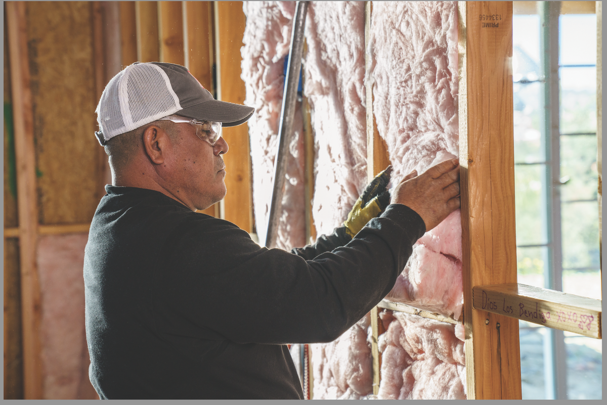 A contractor installing Owens Corning PINK NextGen Fiberglas insulation.