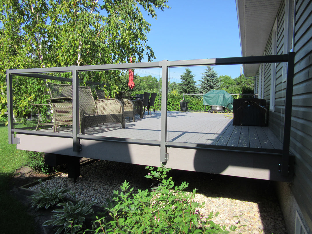 Backyard deck with outdoor furniture and railing, surrounded by greenery.
