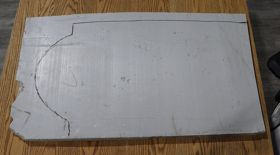 Large piece of foam board with cut-out shape on a wooden surface