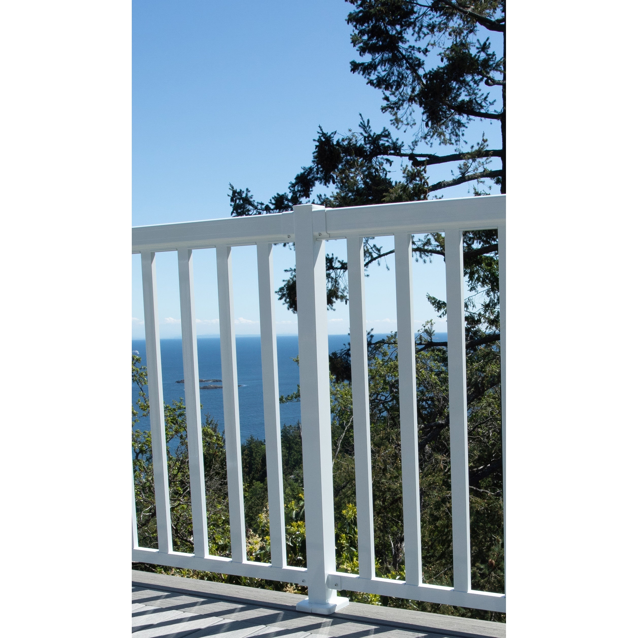 The Regal Rail Line Post in white (for 36" height) from Regal Rail creates an ideal aluminum deck railing for enjoying ocean views, distant islands, and tall trees under a clear blue sky.