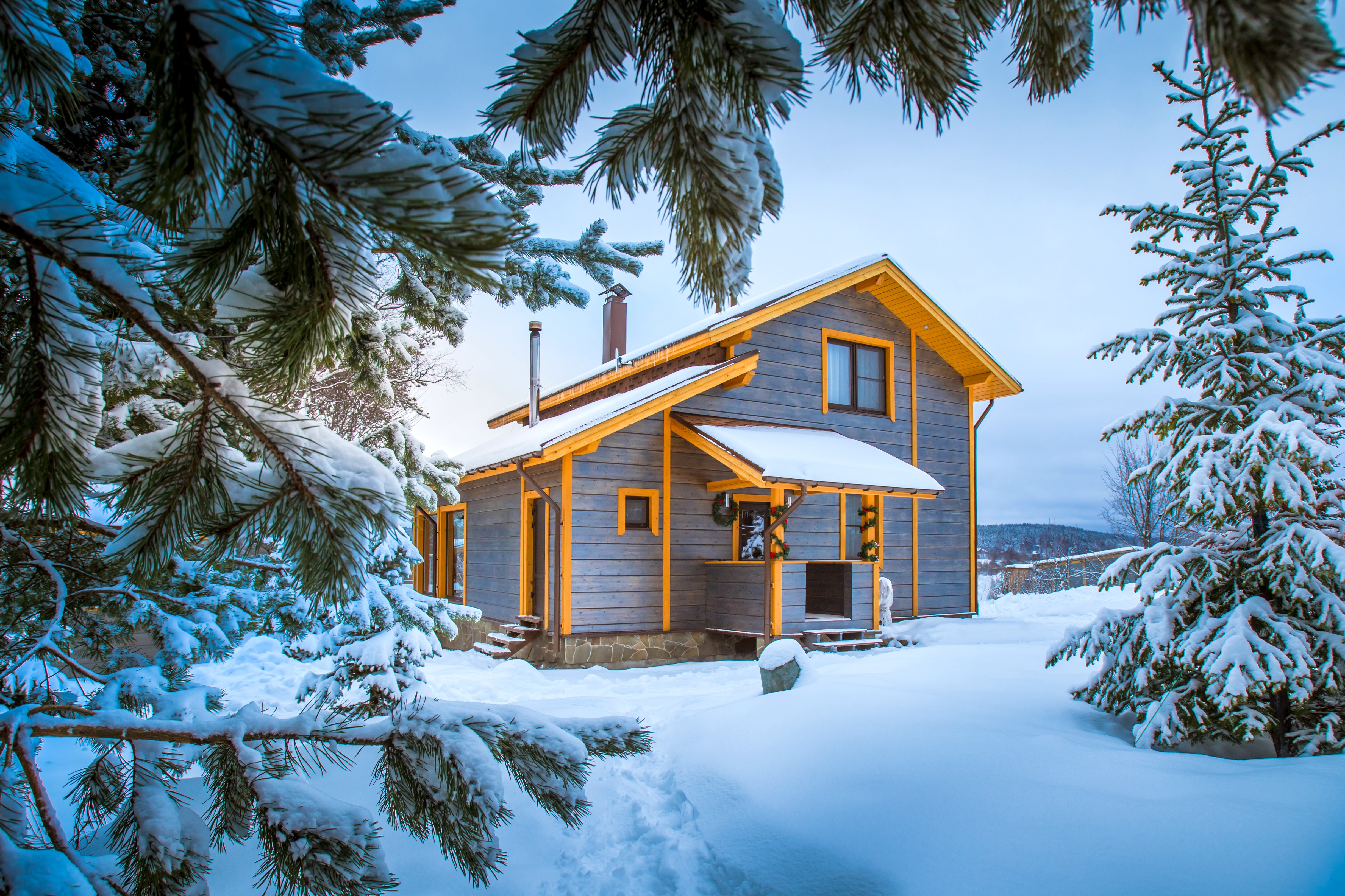 Wooden cabin in a snowy landscape with evergreen trees.