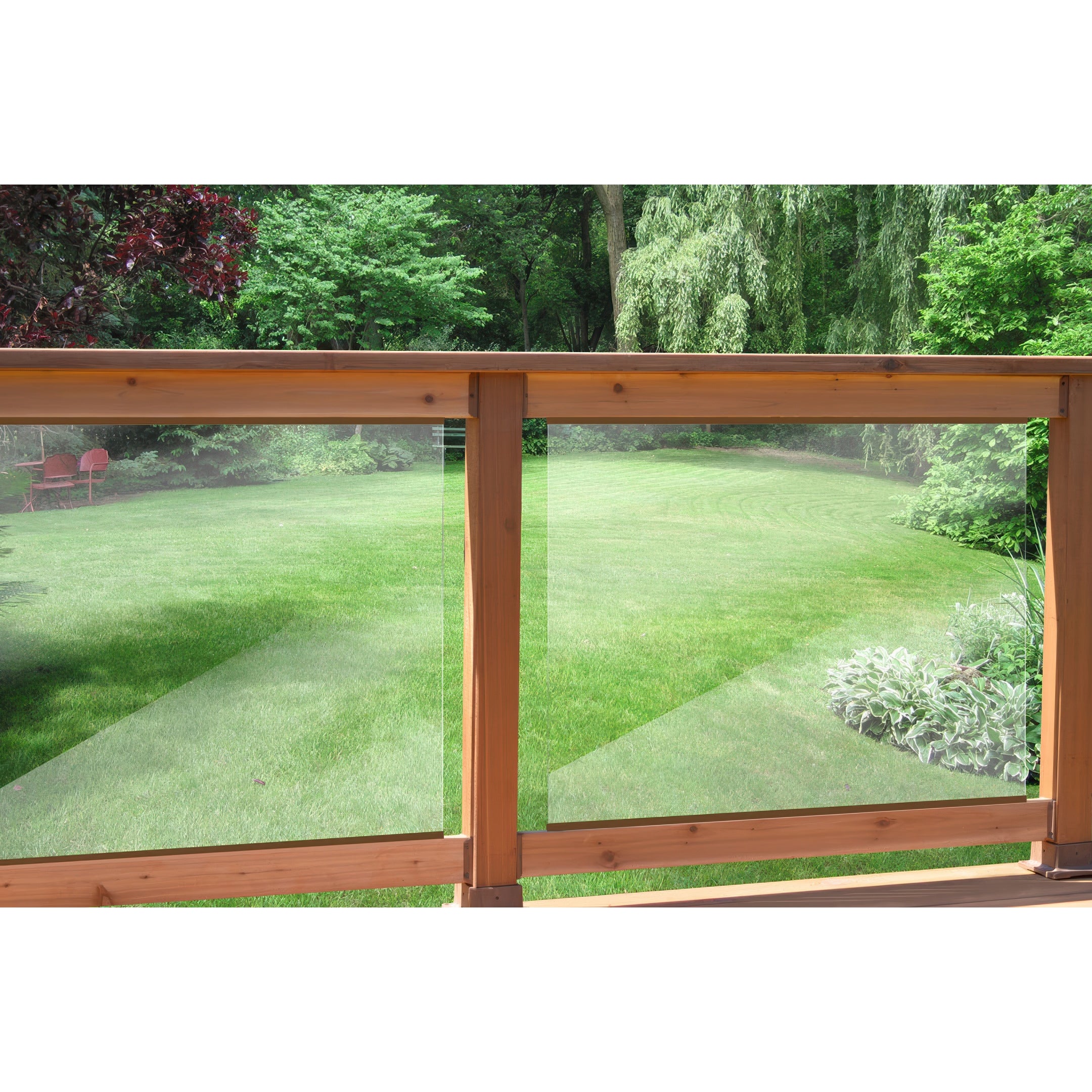 Enjoy the view from a Regal Rail balcony featuring 36-7/8"X27" clear tempered glass panels (for 42" height), overlooking a manicured lawn, lush trees, bushes, and two red chairs shaded in the background.