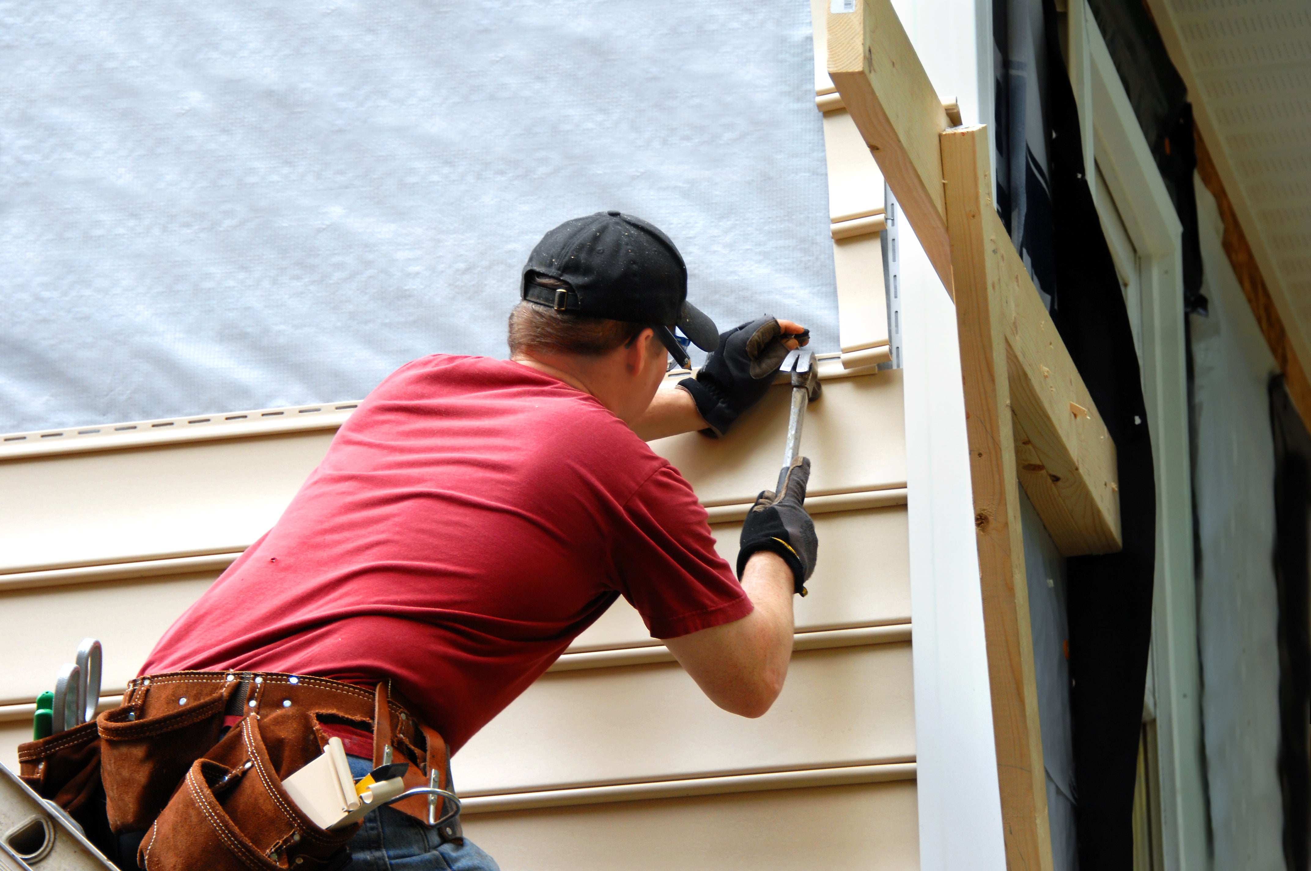 Person installing siding on a house