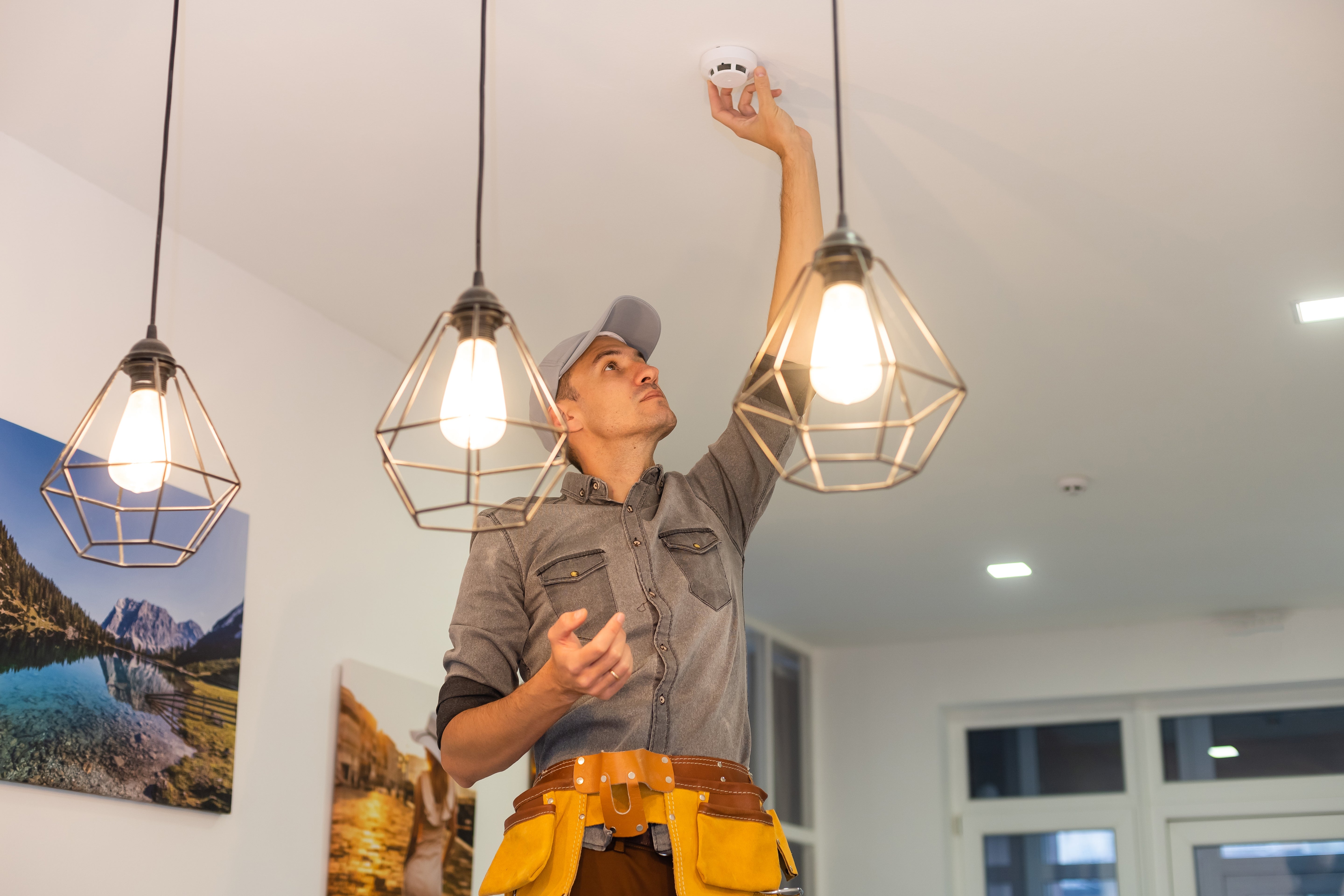 Person installing a light fixture in a room with decor elements.
