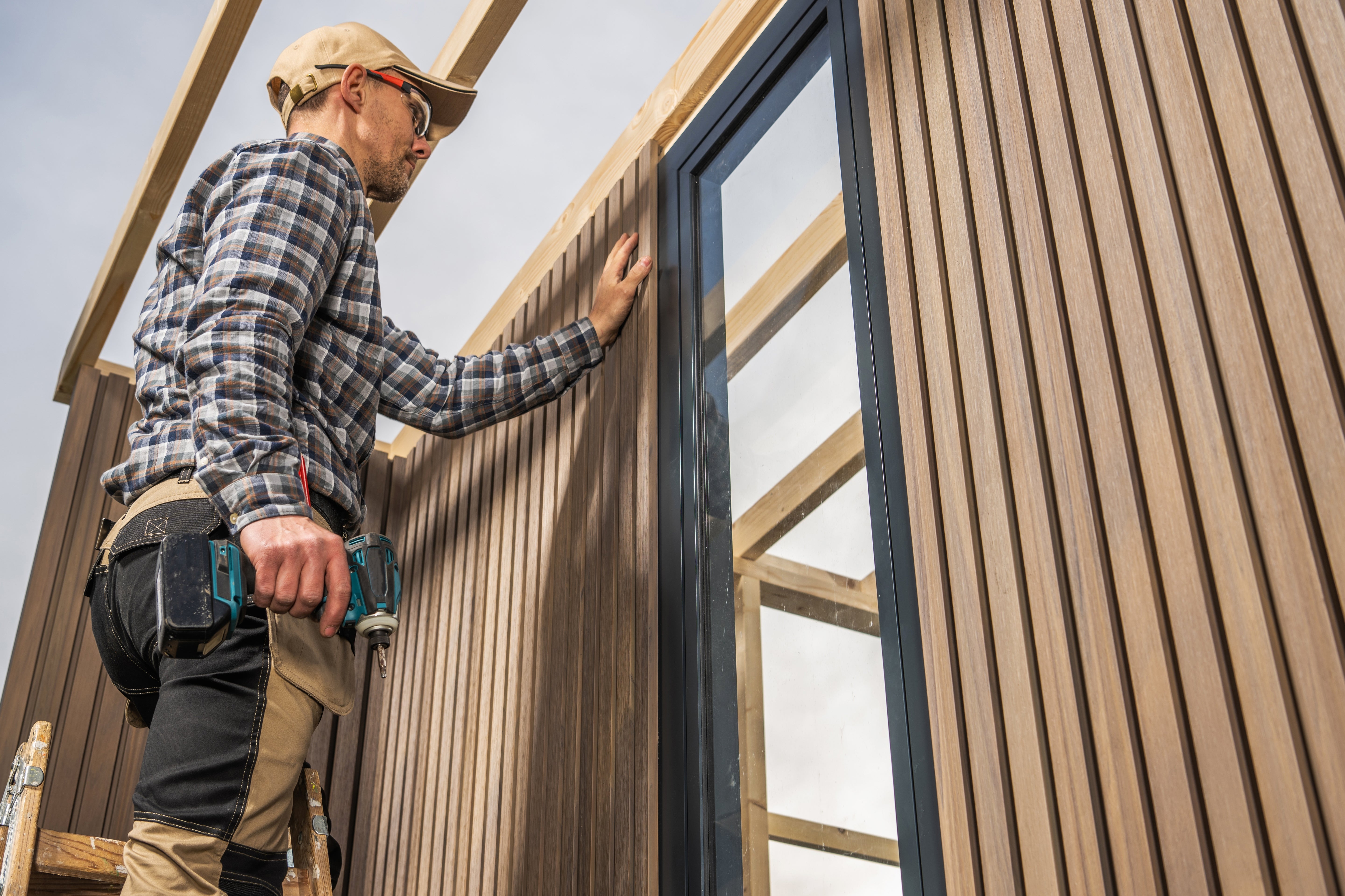 Contractor installing siding on a framed shed with a window