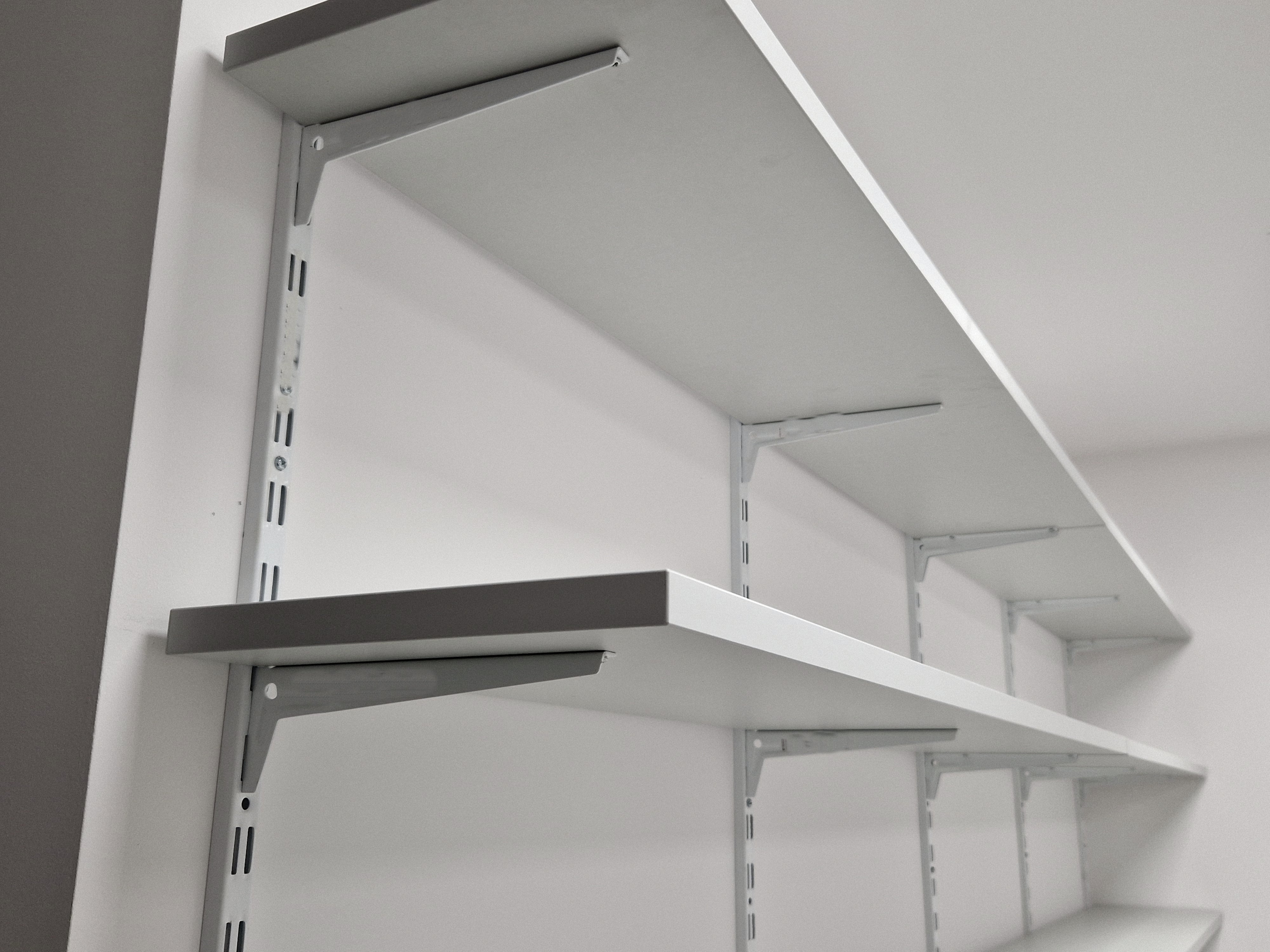 Metal shelving unit with adjustable shelves against a neutral wall.