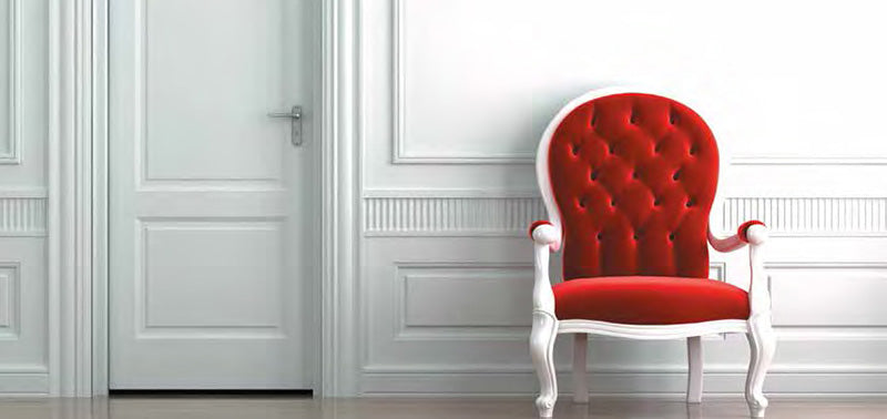 A background image of elaborate trim and an interior door accompanied by a vibrant red chair